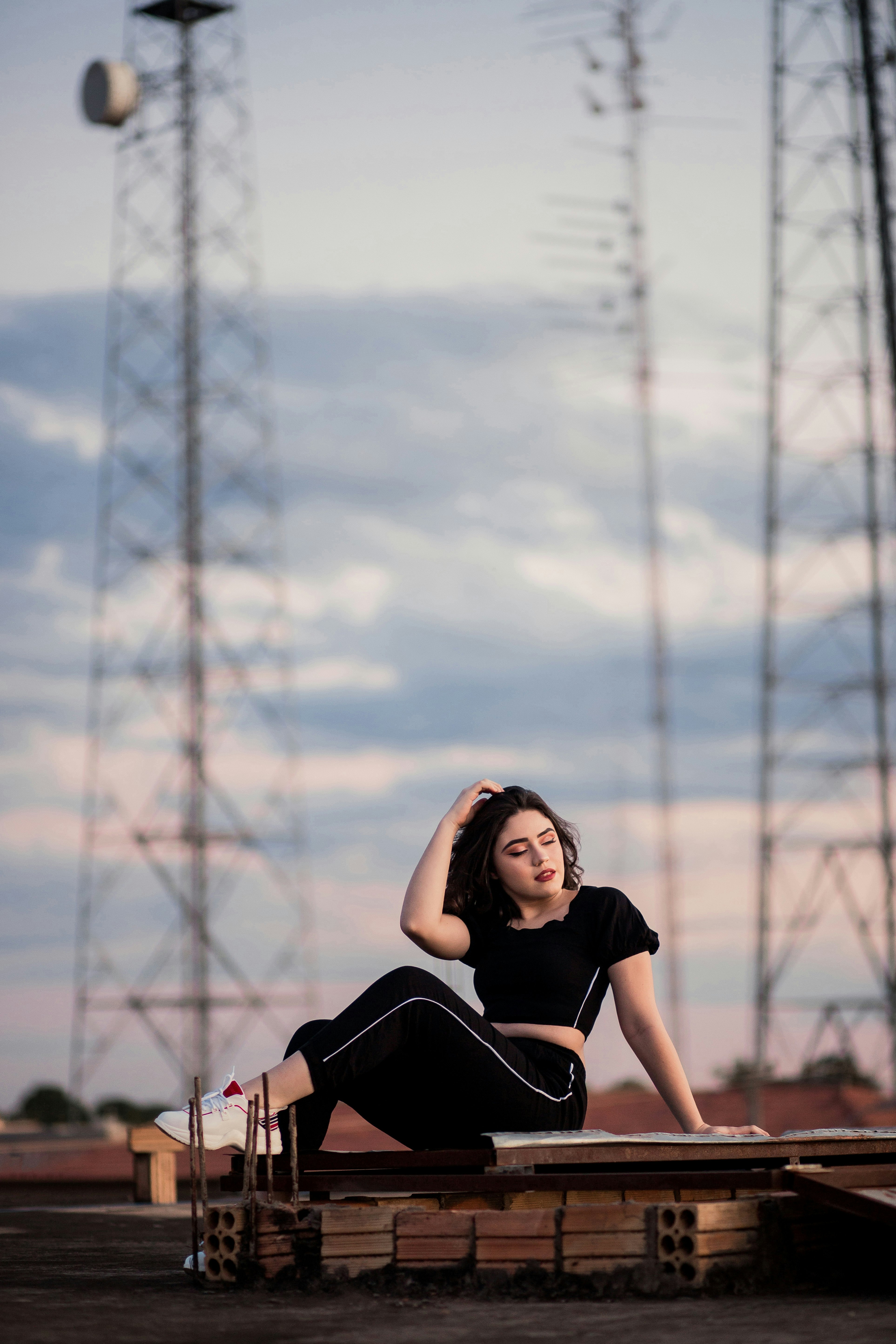 woman in black t-shirt and black pants sitting on ground near tower during daytime